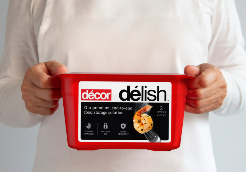 Decor "Delish" microwave container held by two hands waist high.